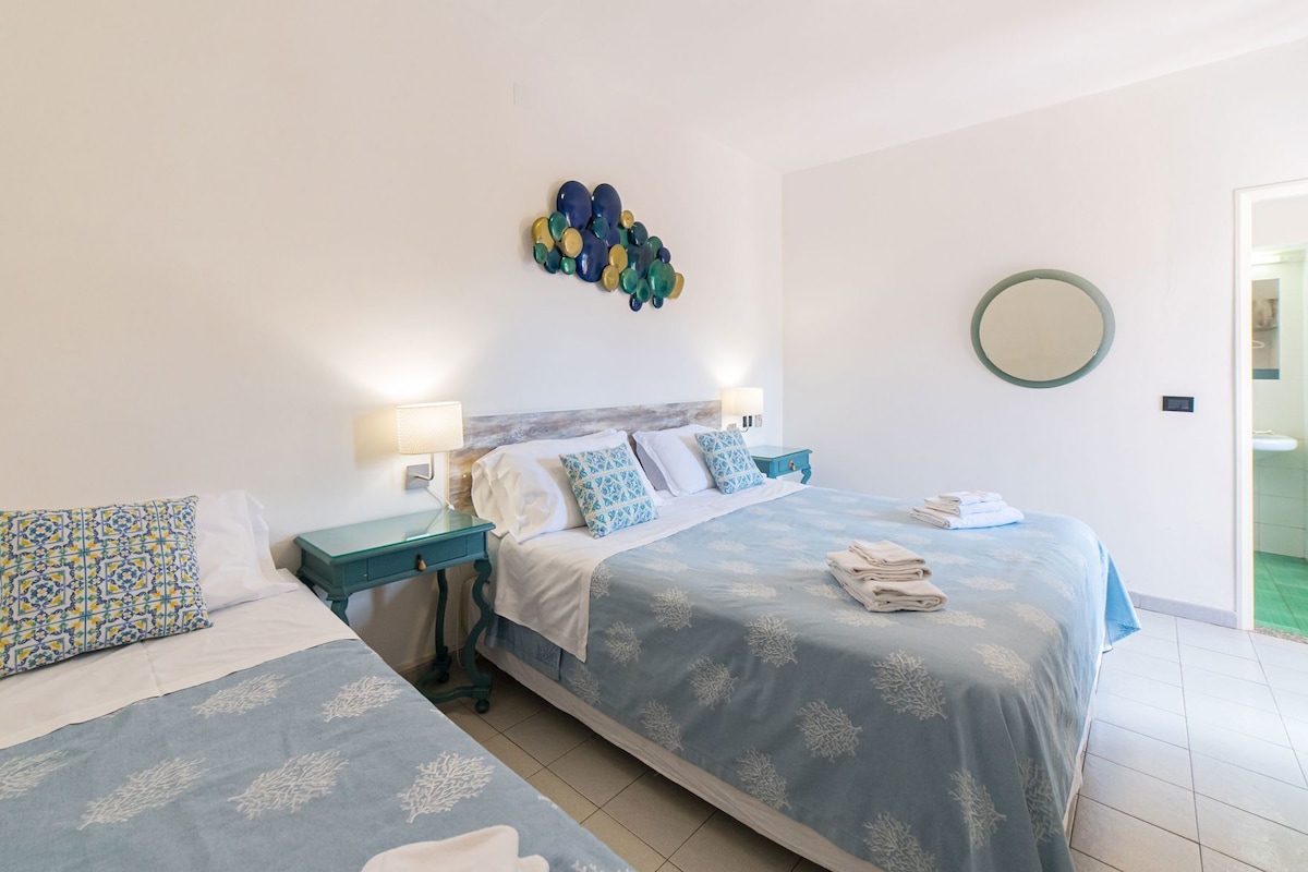 Habitación de hotel con dos camas, un espejo redondo y un adorno de pared.