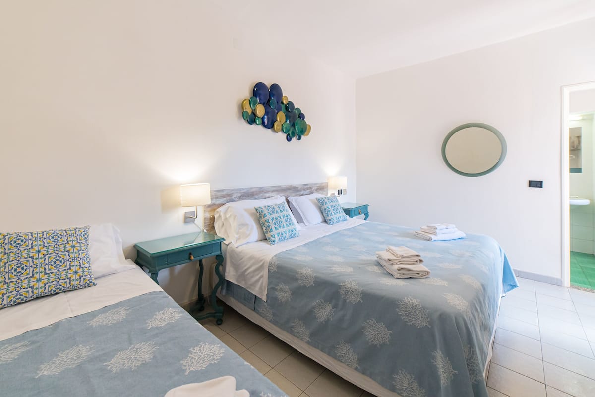 Habitación de hotel con dos camas, un espejo montado en la pared y un adorno mural.