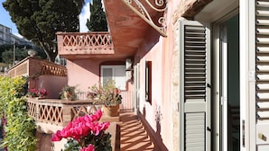 A building with a balcony, potted plants, and a door.