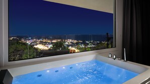 A bathroom with a large bathtub, a window with a city view, and a shower area. - Pefkos View Suites & Maisonette (Rhodes)