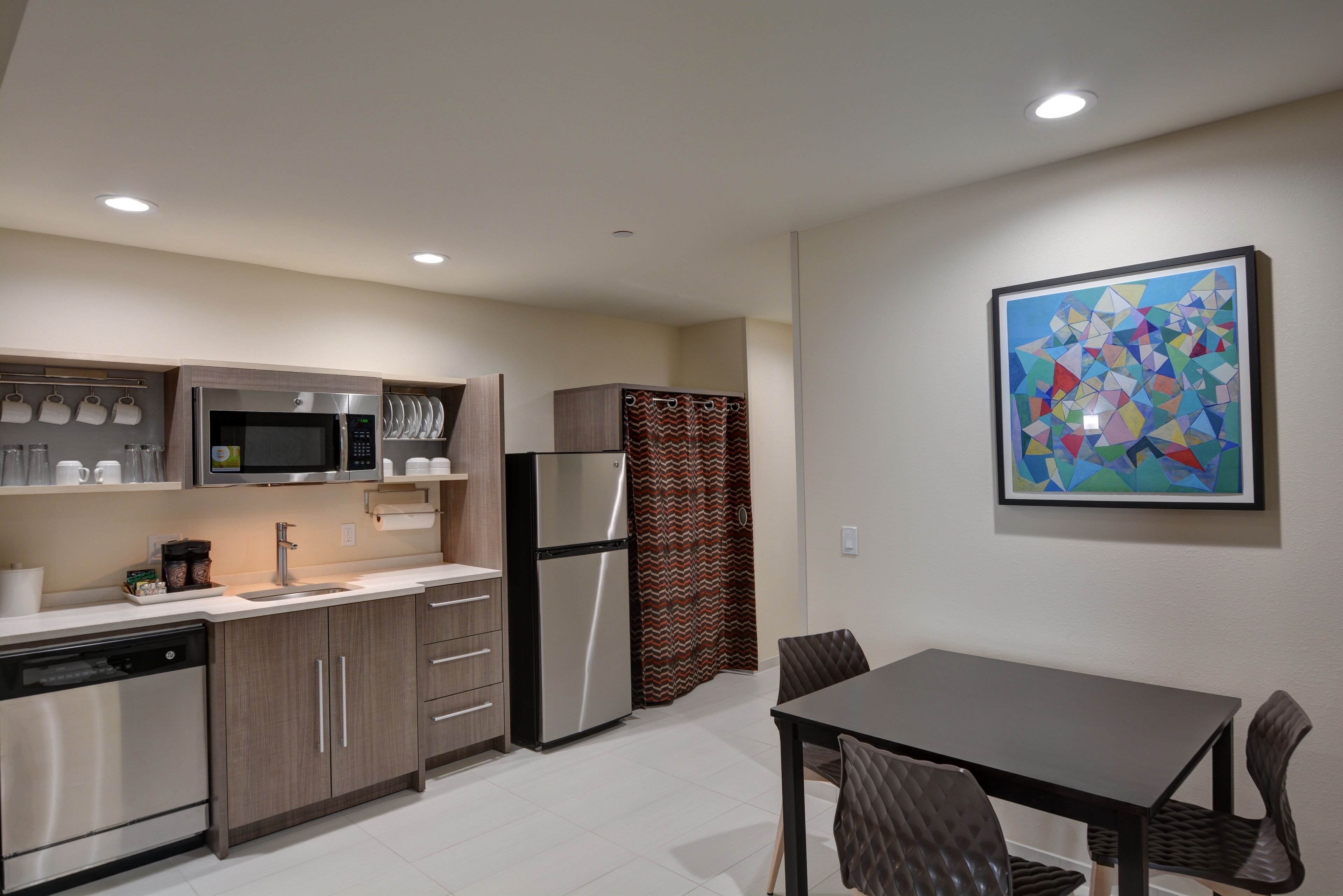 A modern kitchen with stainless steel appliances, wooden cabinets, and a dining area with a table and chairs.