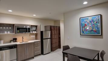 A modern kitchen with stainless steel appliances, wooden cabinets, and a dining area with a table and chairs.