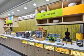 A breakfast buffet area with a 'Good Morning' sign, a self-service beverage station, and a variety of food items displayed in clear containers. - Home2 Suites by Hilton OKC Midwest City Tinker AFB (Midwest City)
