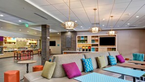 Un moderno vestíbulo de hotel con zona de estar, cocina y bar.