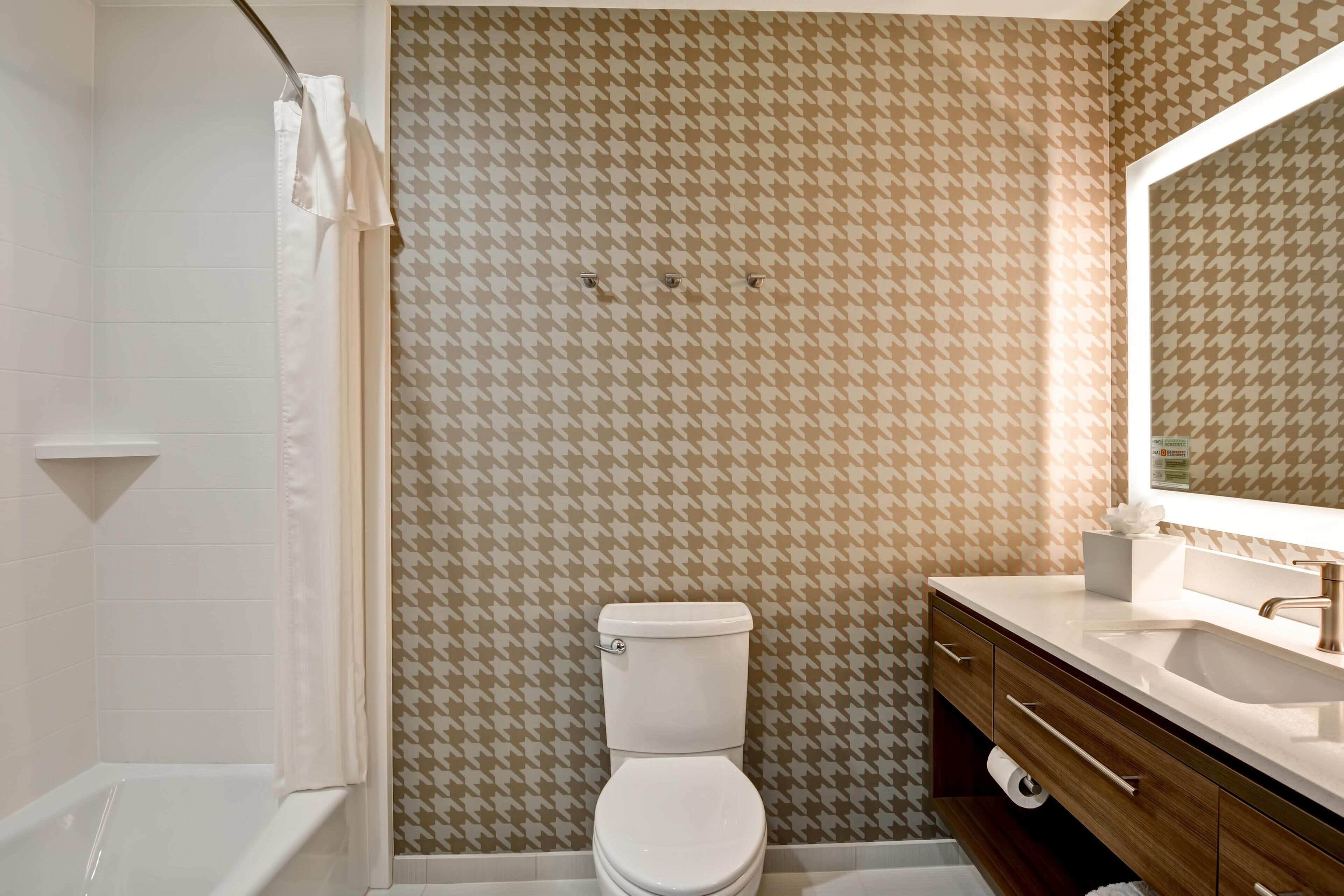 Un baño con pared estampada, inodoro, lavabo y espejo.