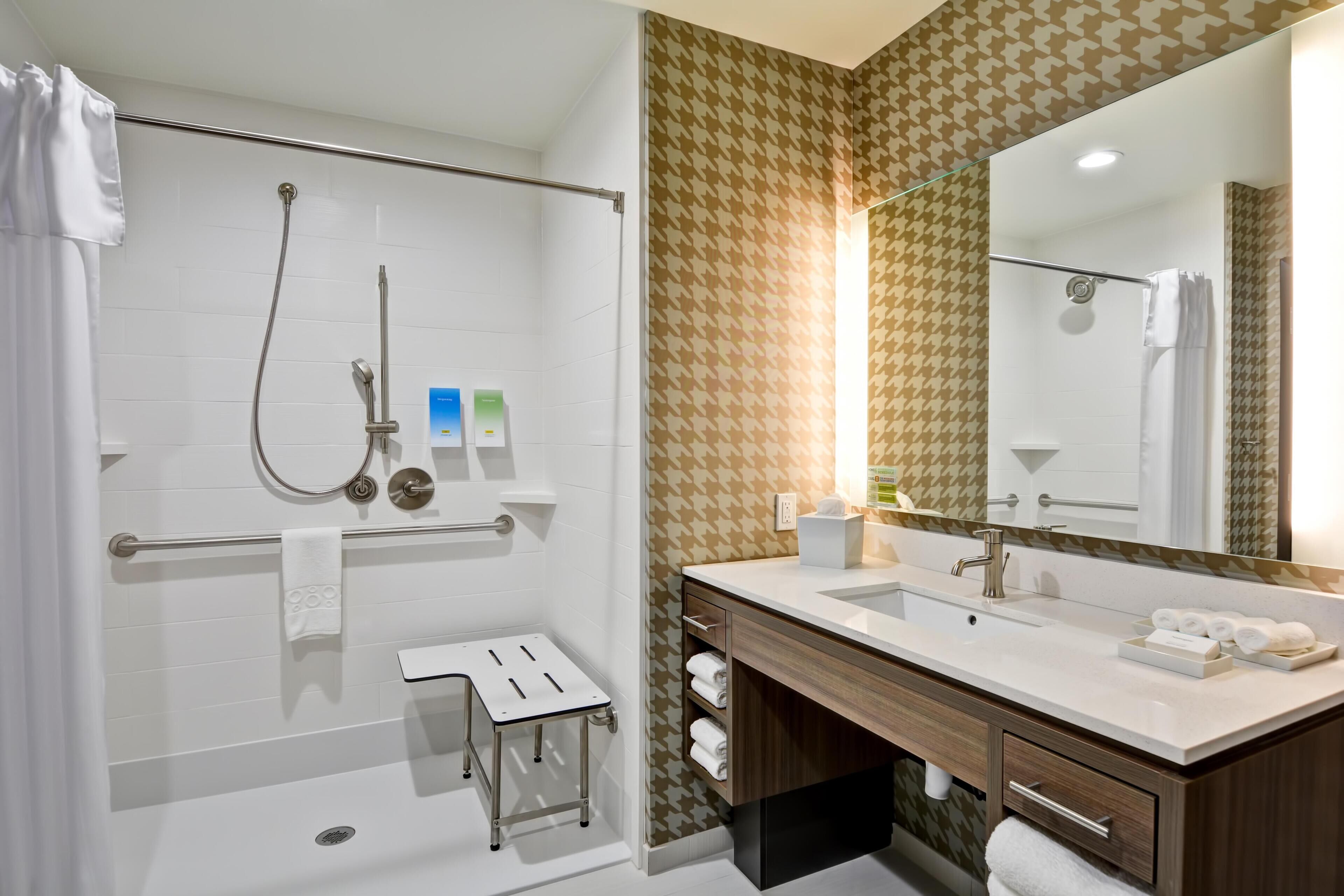 Un bagno moderno con doccia, un mobile vanità con specchio e un portascopevoli.