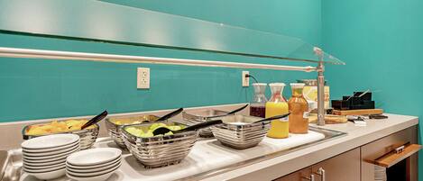 A buffet setup with various food items and serving utensils.