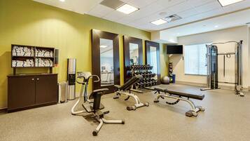 A gym with exercise equipment, a water dispenser, and a mirror wall.