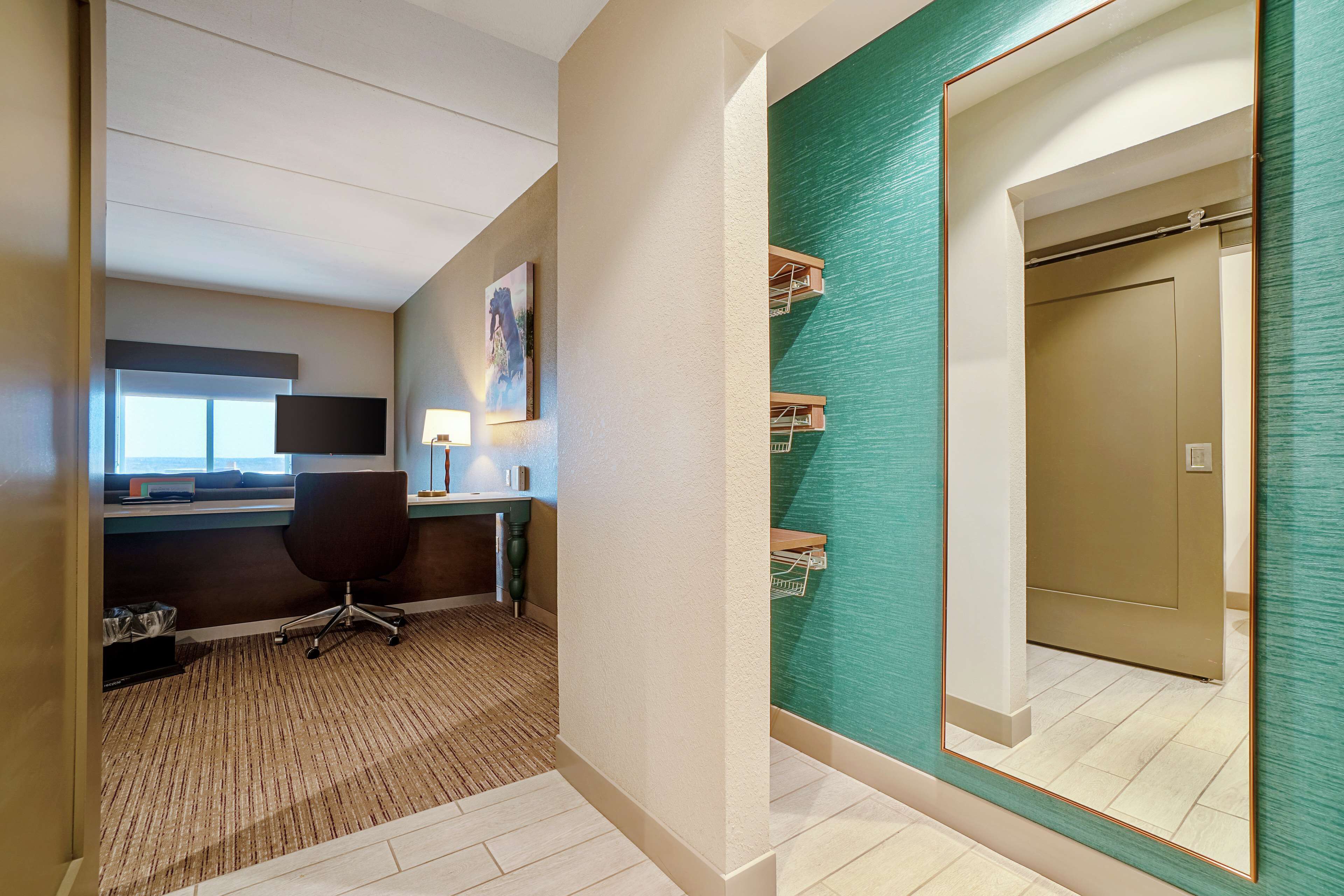 Une chambre d’hôtel équipée d’un bureau, d’une chaise et d’un grand miroir.
