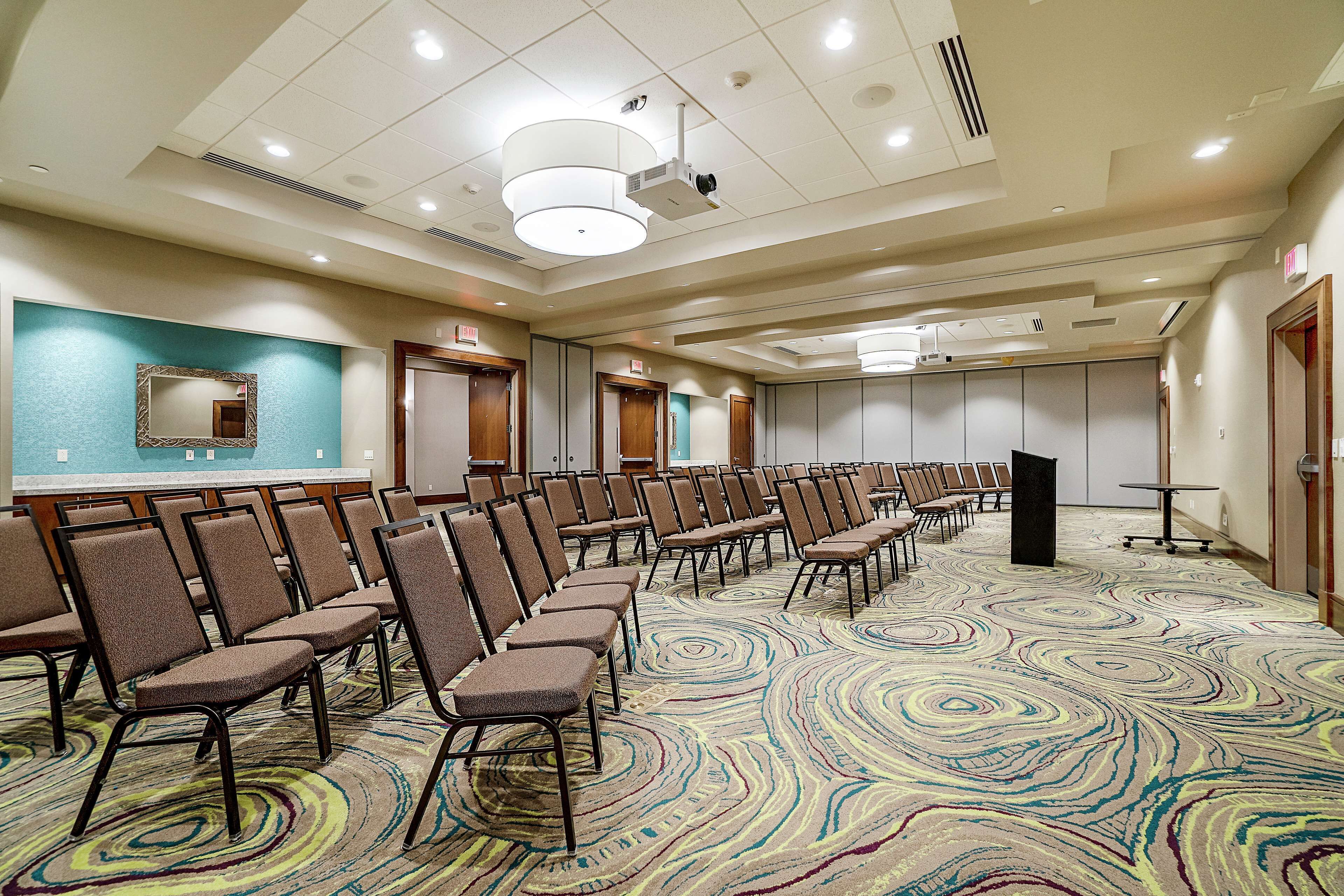 A conference room with rows of chairs, a podium, and a carpeted floor.
