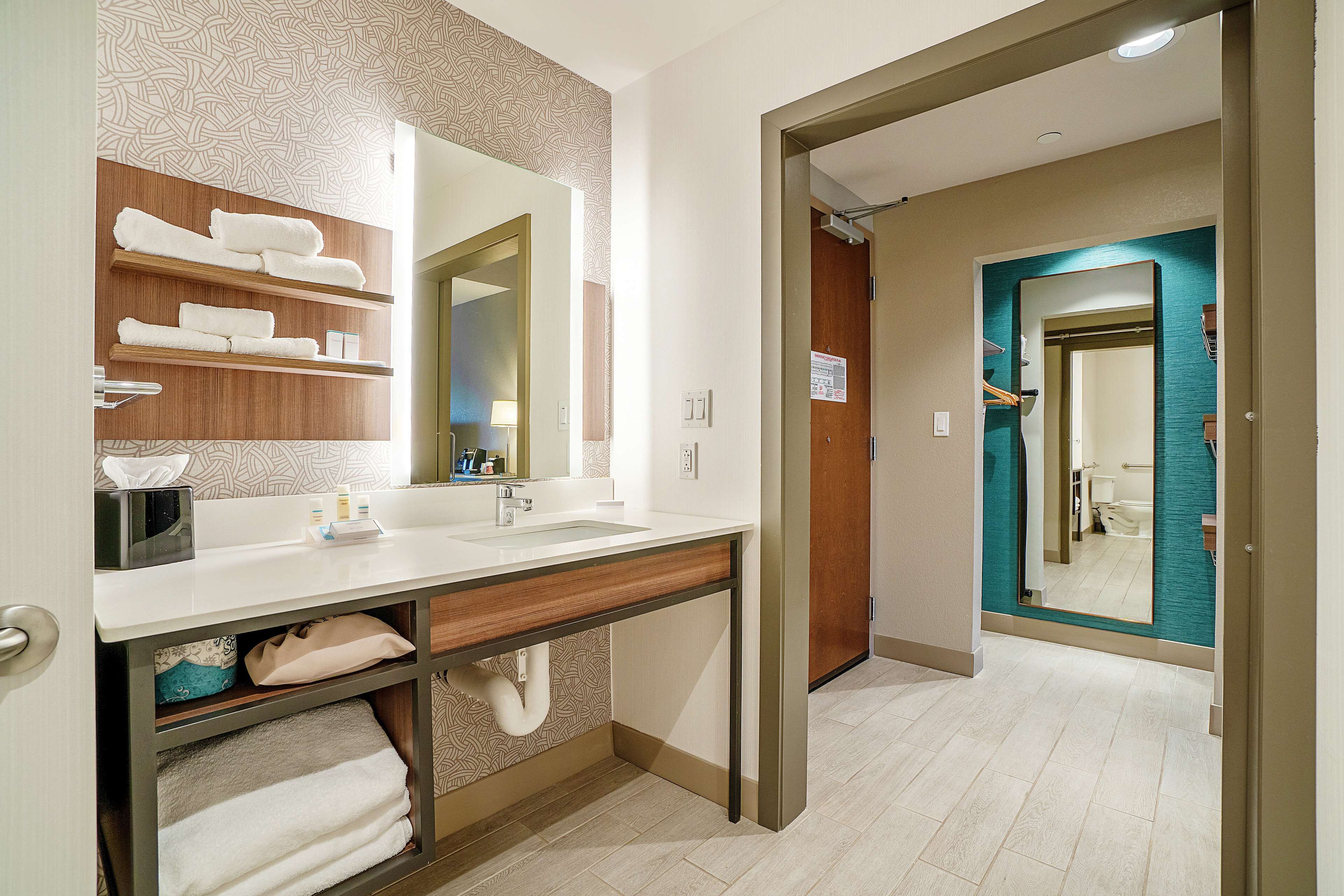 Een moderne badkamer met een houten wastafelmeubel, een grote spiegel en een handdoekrek.