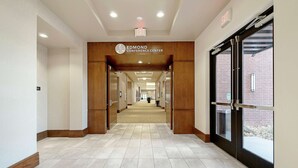 A hallway leading to the Edmond Conference Center with a tiled floor, wooden walls, and a glass door on the right. - Hilton Garden Inn Edmond / Oklahoma City North, OK (Edmond)