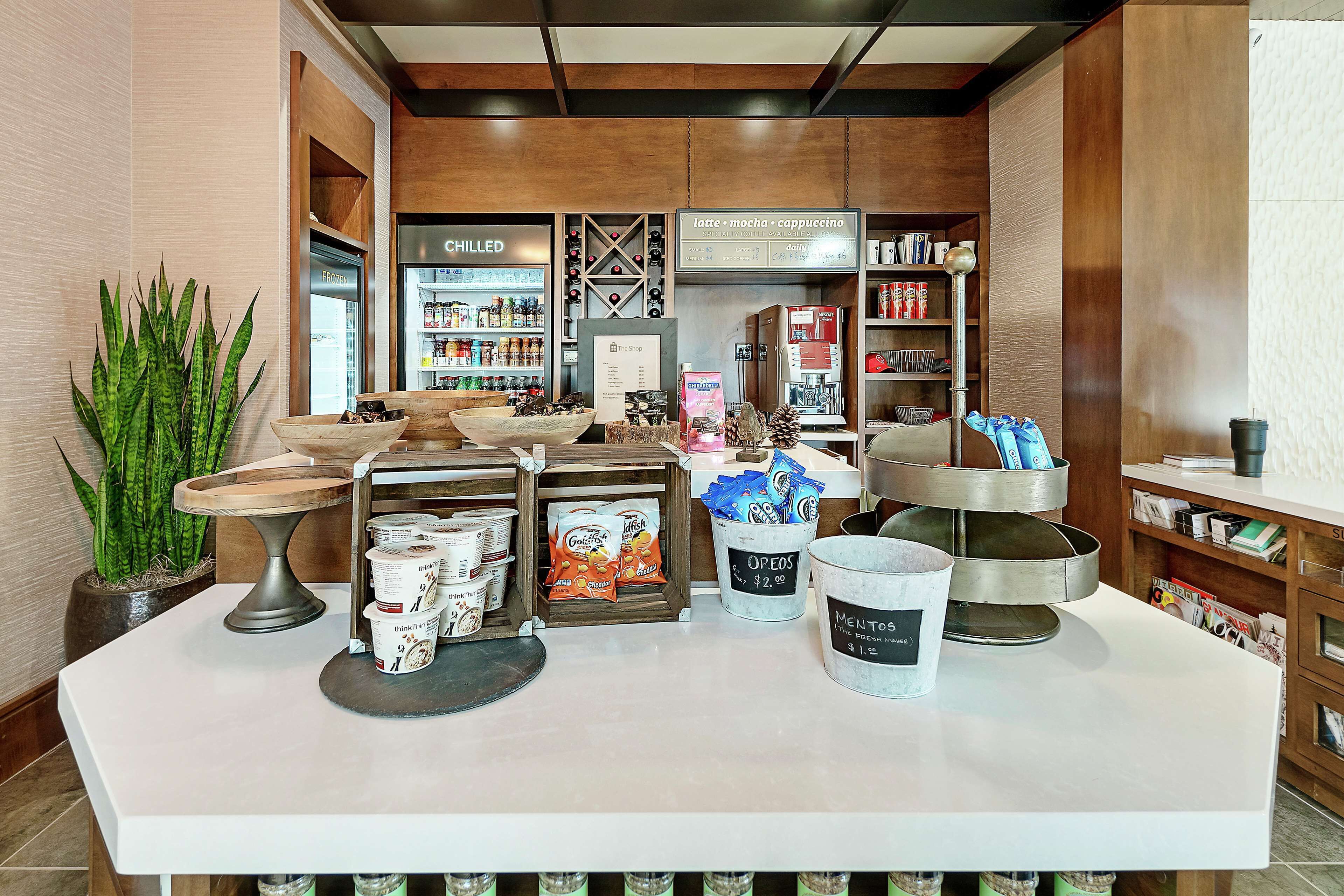 Ein Café-Interieur mit einer Theke, auf der Kaffeetassen, eine Pflanze und verschiedene Kaffeebedarfsartikel präsentiert werden.