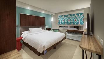 Una habitación de hotel moderna con una cama grande, un escritorio y un televisor.