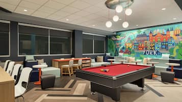 A pool table in a modern lounge area with seating and a mural of a cityscape.