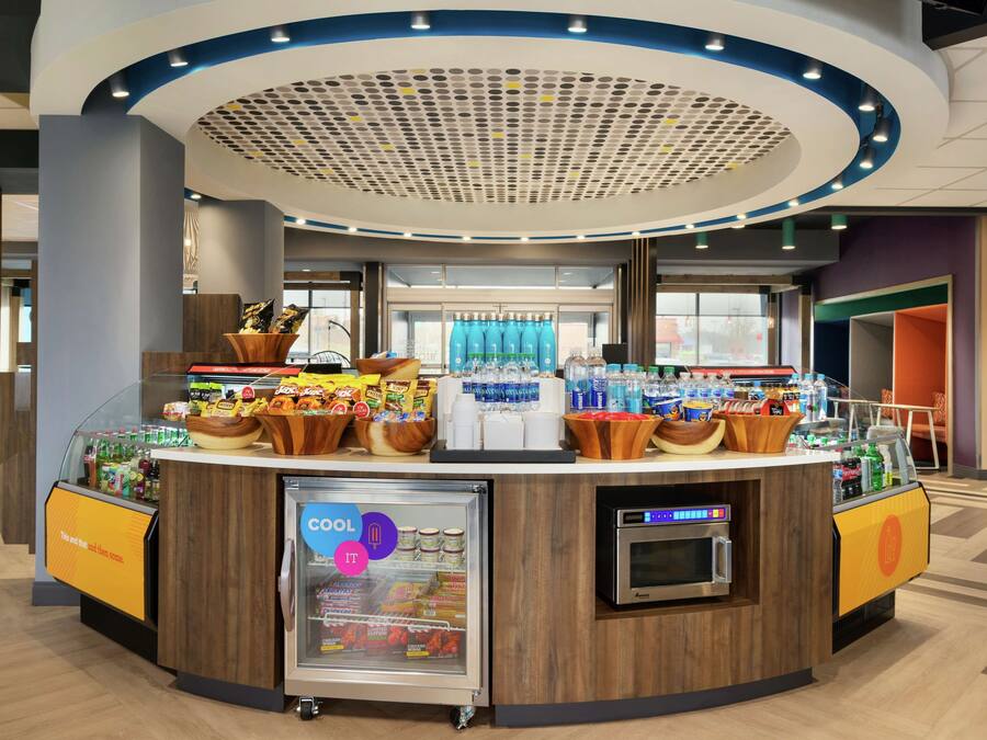 Eine Selbstbedienungsstation für Getränke mit einem Kühlregal, einer Kaffeemaschine und verschiedenen Snacks.
