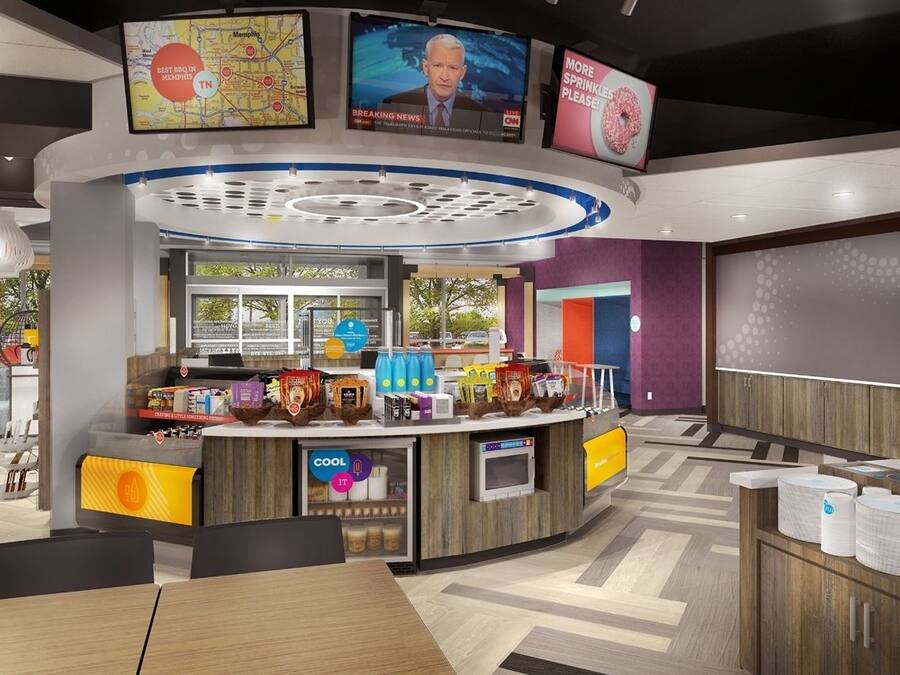 A modern restaurant with a central counter, seating area, and a TV screen displaying news.