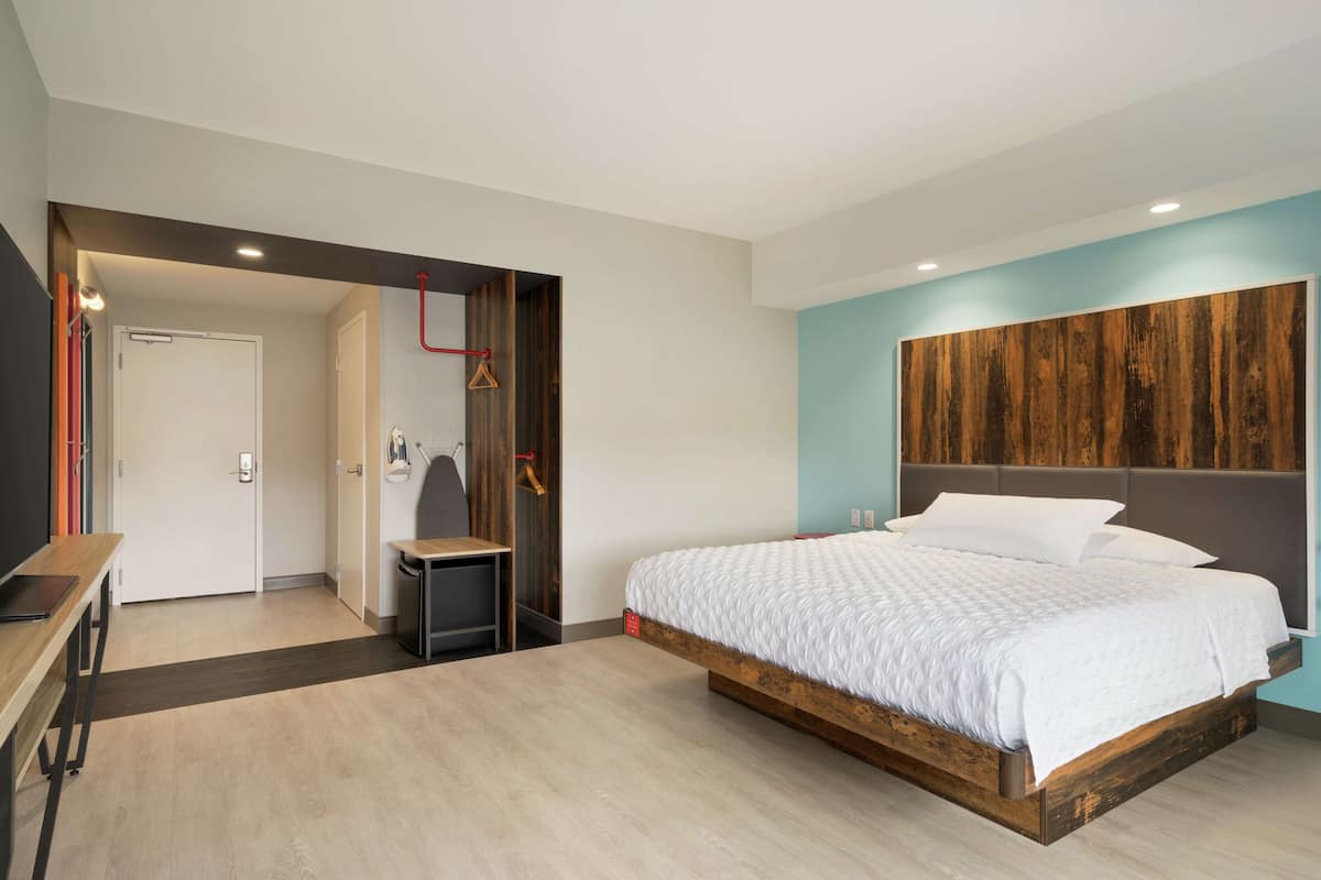 A modern bedroom with a large bed, a desk, and a wardrobe.
