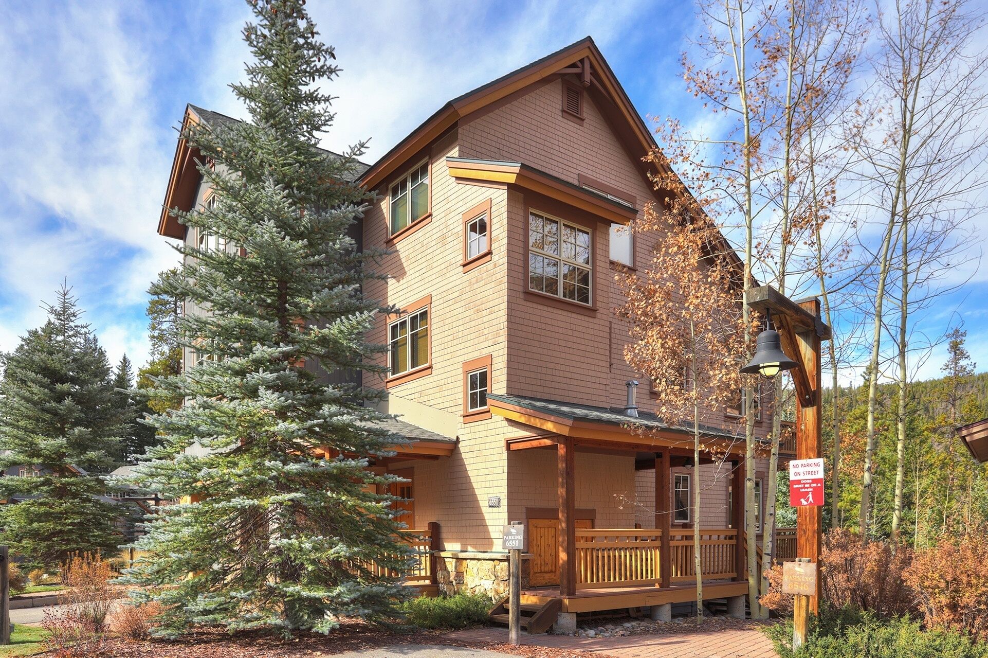 A two-story lodge with a wooden exterior, a porch, and a sign indicating no parking on the street.