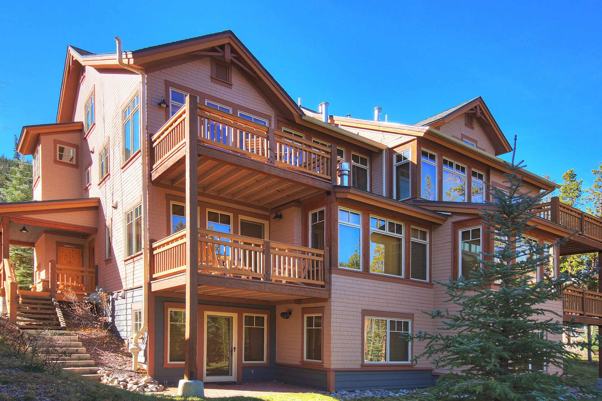 A multi-story house with a balcony, large windows, and a stone foundation.