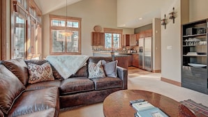A spacious living room with a leather sofa, a coffee table, and a kitchen in the background. - Settlers Creek (Keystone)
