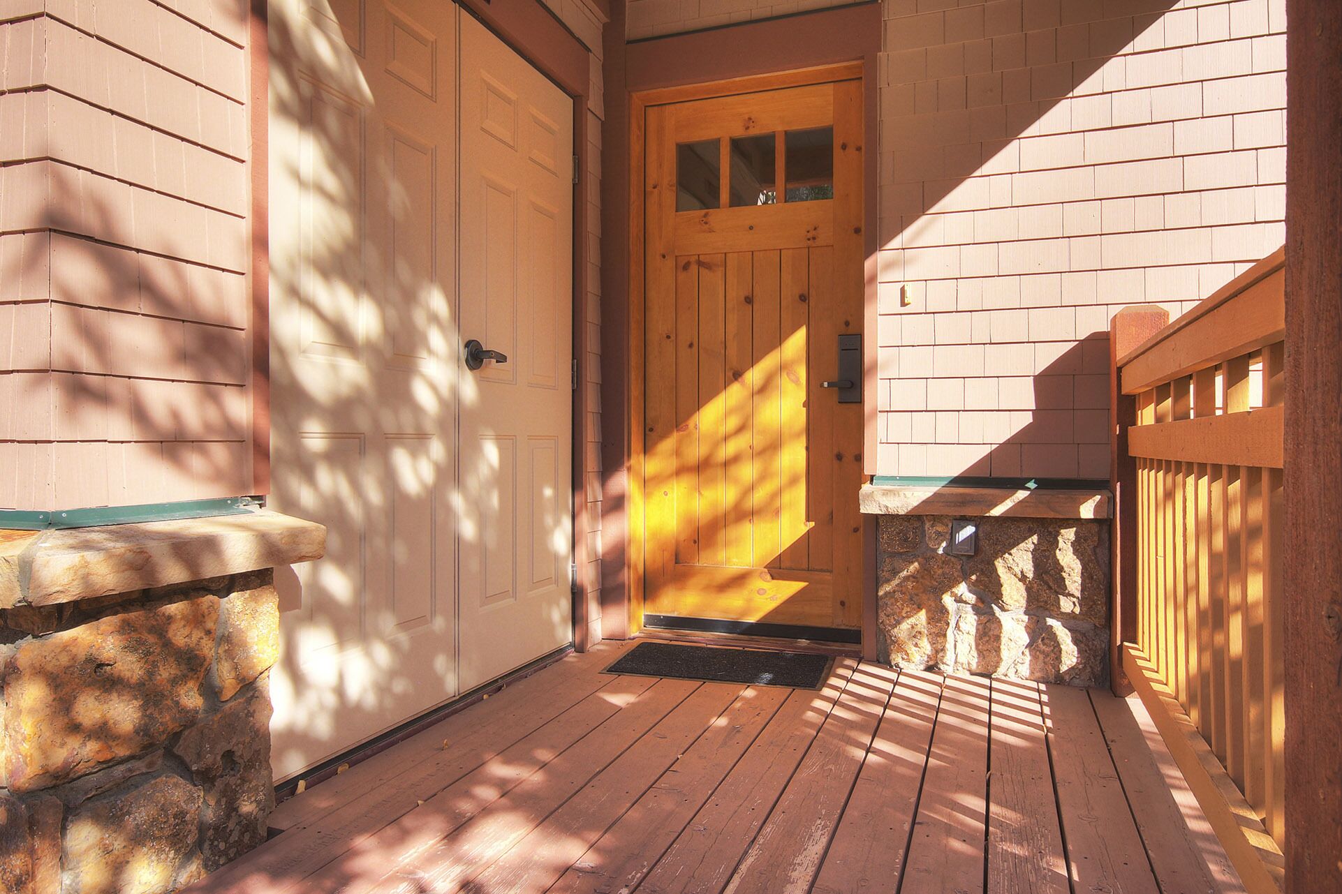 Une porte en bois avec une fenêtre, un mur en pierre et une terrasse en bois.
