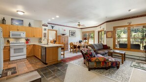 Una cocina amplia con armarios de madera, microondas y comedor con mesa y sillas.