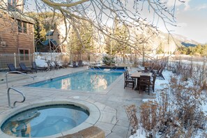 A swimming pool with a hot tub, surrounded by lounge chairs and a table, with a mountain backdrop. - 2296 Red Hawk Lodge 2 Bedroom Condo by RedAwning (Keystone)