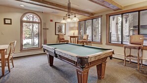 A pool table in a room with large windows, wooden beams, and a chandelier. - 2296 Red Hawk Lodge 2 Bedroom Condo by RedAwning (Keystone)