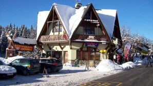 A traditional chalet-style building with a ski school sign, a restaurant sign, and a pension sign. - Pension Rotunda (Harrachov)