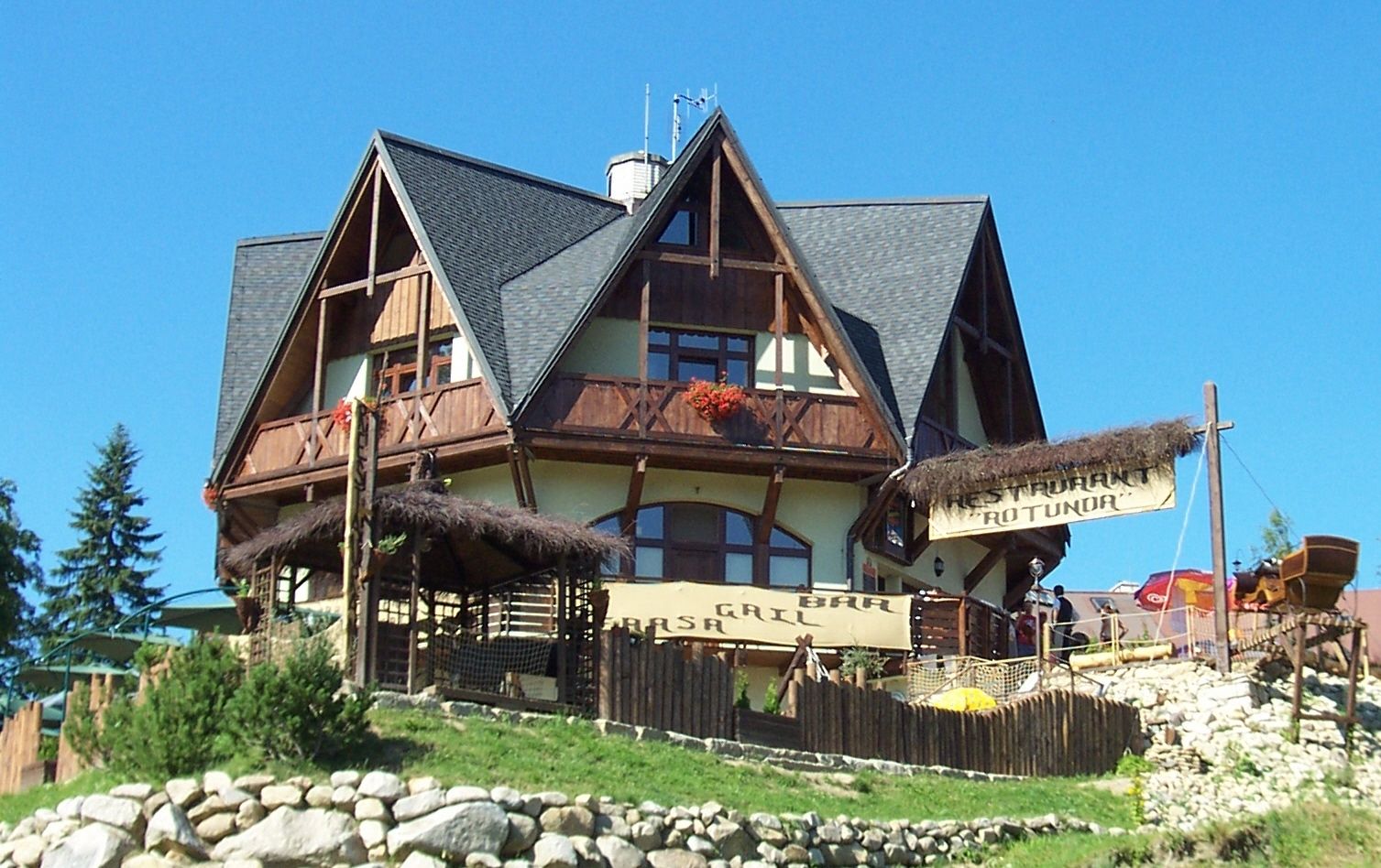 A traditional chalet-style building with a thatched roof, a bar, and a restaurant sign.