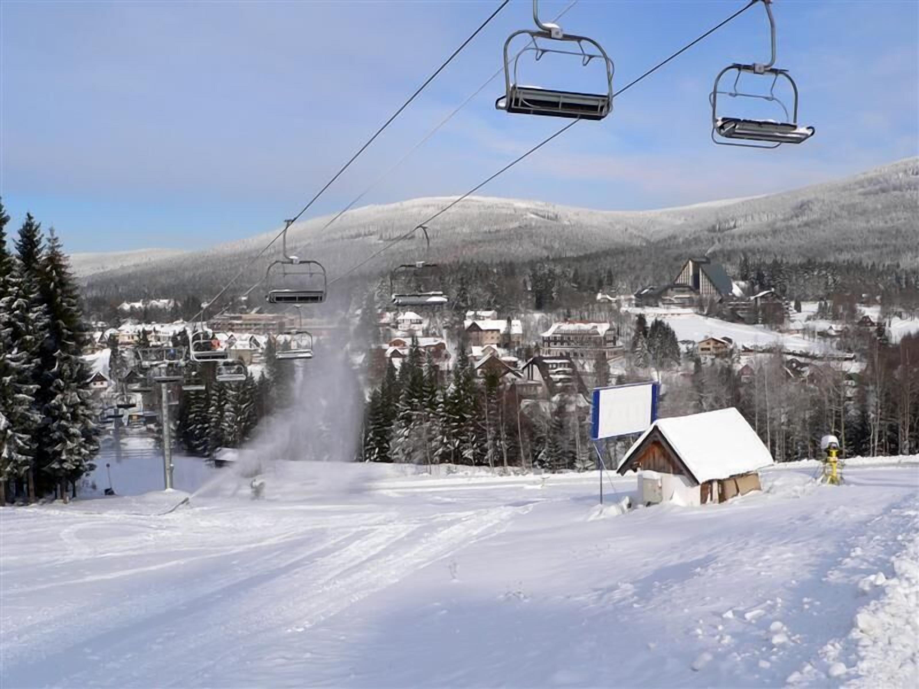 A ski lift with cabins and a snowy village below.