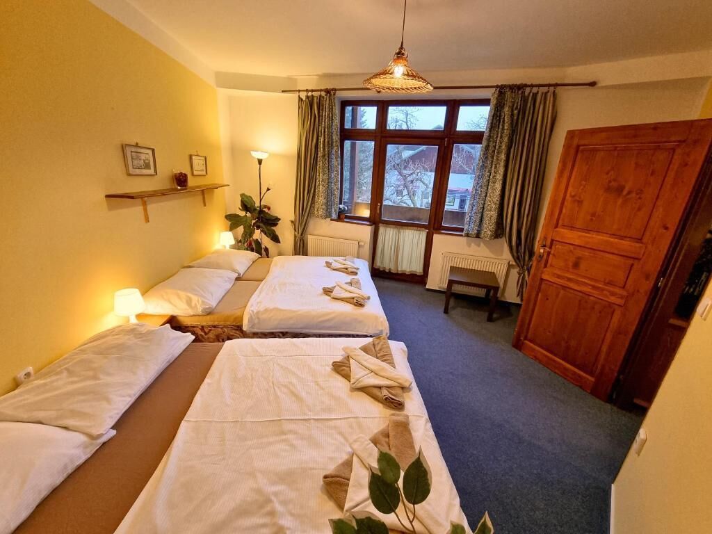 Una habitación de hotel con dos camas, una ventana con cortinas, una puerta de madera y una planta.