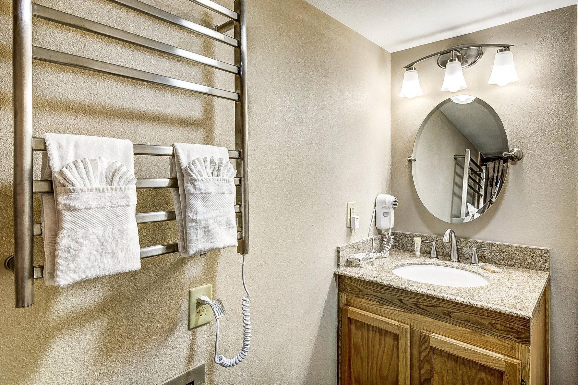 A bathroom with a towel rack, a mirror, a sink, and a hairdryer.