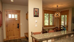 A kitchen with a granite countertop, wooden chairs, a wooden door, and a window with a view of trees. - 6532 Settlers Creek Townhomes 2 Bedroom Condo by RedAwning (Keystone)