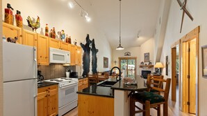 A spacious kitchen with wooden cabinets, a central island, and a microwave. - 2674 Tenderfoot Lodge 2 Bedroom Condo by RedAwning (Keystone)