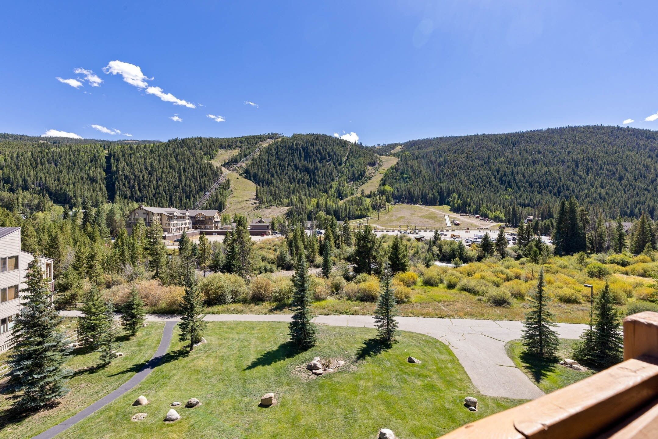 A mountainous landscape with a ski resort, including buildings, trails, and trees.