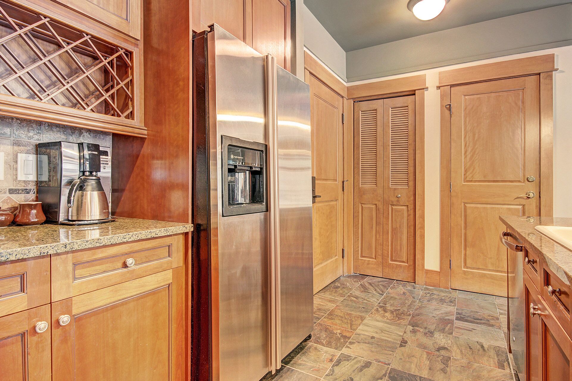 A kitchen with wooden cabinets, a stainless steel refrigerator, a coffee maker, and a built-in oven.