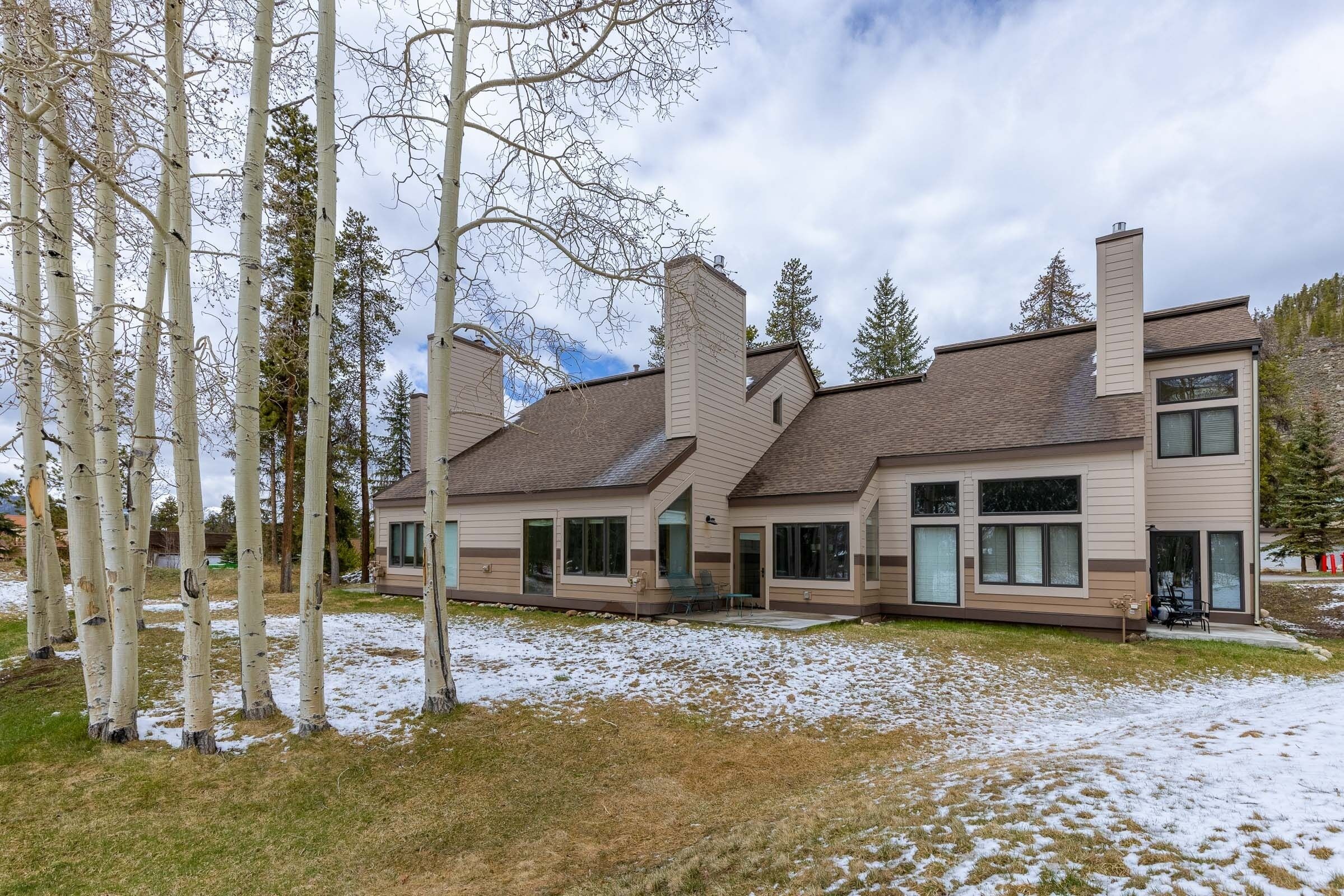 Ein modernes, zweistöckiges Haus mit einer großen Veranda, mehreren Schornsteinen und einem mit Schnee bedeckten Rasen.