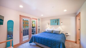 A bedroom with a bed, a window, a door, and a ski rack.