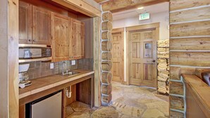 A rustic kitchen with wooden cabinets, a stone backsplash, and a built-in microwave.