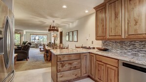 A spacious kitchen with wooden cabinets, a granite countertop, and a built-in dishwasher. - 221 Cinnamon Ridge I 2 Bedroom Condo by RedAwning (Keystone)