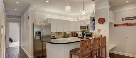 A modern kitchen with a central island, stainless steel appliances, and pendant lighting.