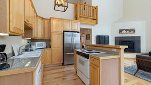 A modern kitchen with wooden cabinets, a stainless steel refrigerator, a microwave, and a gas stove. - 130 Meisel Drive 4 Bedroom Townhouse by RedAwning (Keystone)