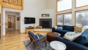 A spacious living room with a wooden staircase, a fireplace, a large window, and a cozy seating area. - 130 Meisel Drive 4 Bedroom Townhouse by RedAwning (Keystone)