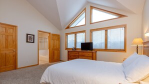 A bedroom with a large bed, wooden wardrobe, a TV on a dresser, and skylights. - 130 Meisel Drive 4 Bedroom Townhouse by RedAwning (Keystone)