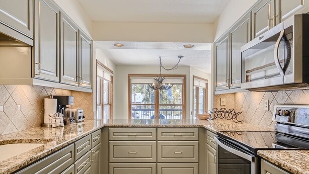 A kitchen with a central island, double ovens, and a microwave. - 1655 Quicksilver 3 Bedroom Condo (Keystone)