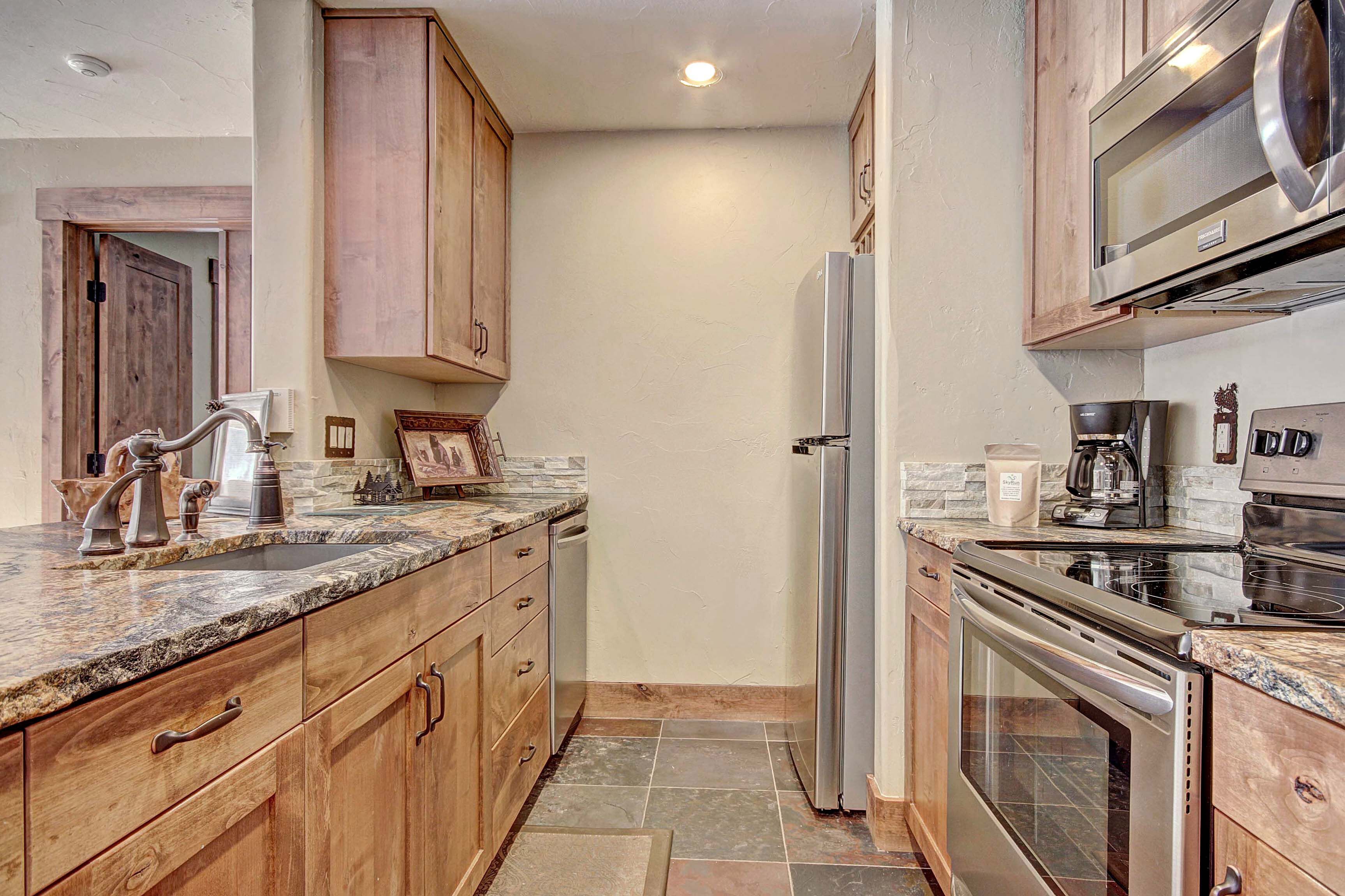 Una cocina con armarios de madera, encimeras de granito, refrigerador de acero inoxidable y horno.