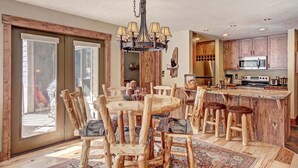 A spacious kitchen with a large island, wooden chairs, and a chandelier.