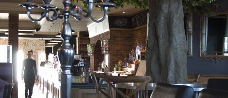 A dining area with a table set for two, a candelabra with lit candles, and a tree in the background.